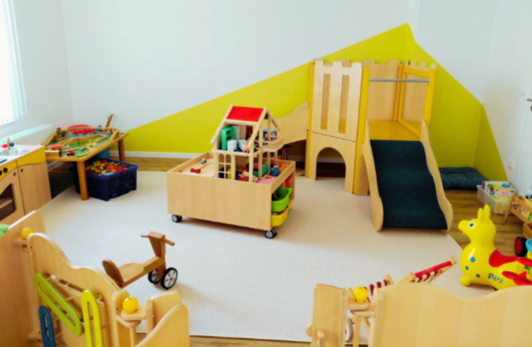 Es ist ein Raum zu sehen, in welchem bunte Kinderspielsachen und einige Kinder-Holzmöbel stehen. E